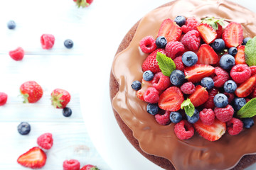 Homemade chocolate cake with berries on white wooden table