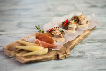 Board with meat pieces. Sliced pear and herbs. Medallions served with roquefort sauce. It's lunch time.