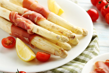 Fresh white asparagus wrapped in jamon on a blue wooden table