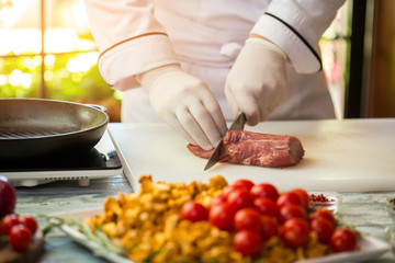 Man cuts raw meat. Hand with kitchen knife. Chef prepares veal for roasting. Working day of cook.