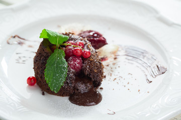 Dessert with red berries. Mint leaves and powdered sugar. Sweet chocolate filling. Dish served with ice cream.