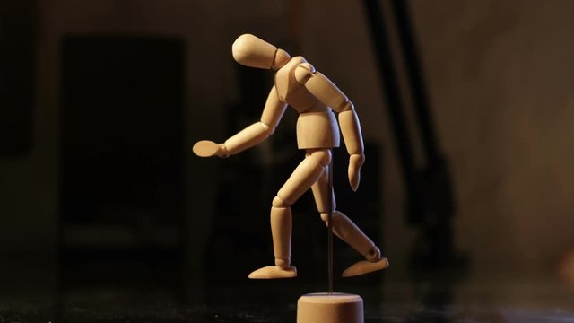 Animated wooden man looks at his hands and feet, then runs, stops to catch his breath.