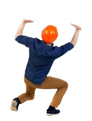 back view business man protective construction helmet protects hands from what is falling from above. engineer in a blue shirt with the sleeves rolled up and a helmet sat down under the weight of the