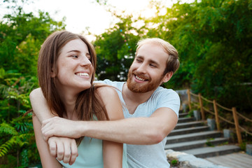 Young beautiful couple embracing, smiling, walking in park. Outdoor background.