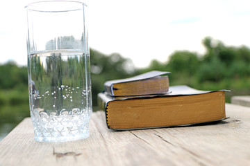 glass of water  close to the book, the Bible