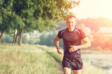 Fototapeta premium Young athletic man jogging in morning park
