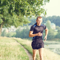 Fototapeta premium Young athletic man jogging in morning park
