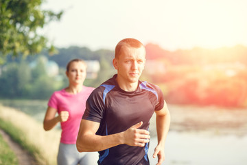 Young athletic people jogging outdoor near pond