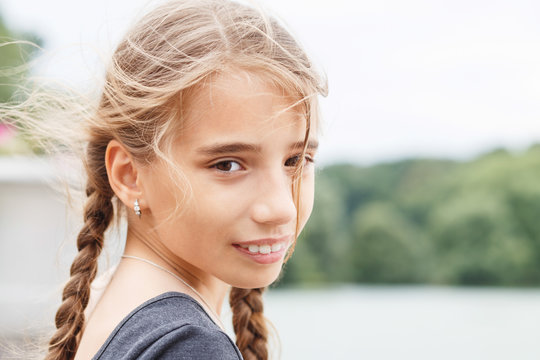 Young happy girl with braids looking into camera