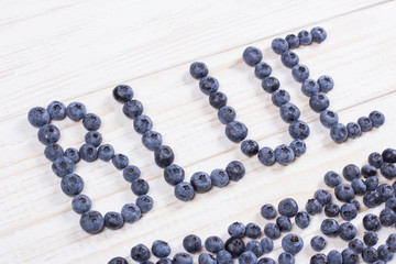 Word blue written letters with blueberries on white wooden board