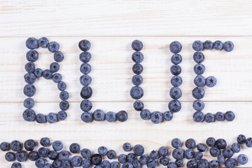 Word blue written letters with blueberries on white wooden board