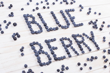 Word blueberry written letters with blueberries on white wooden