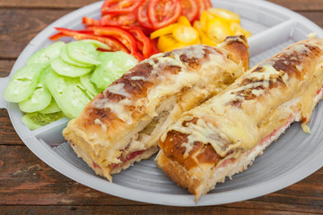 Tasty sandwich with ham, melted cheese and vegetables
