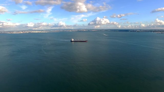 Portugal Lisbon 4k travel video background. Aerial flying over ship cargo tanker in ocean water, city, sky clouds