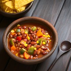 Veganischer Chili aus Kidneybohne, Karotte, Zucchini, Paprika, Mais, Tomate, Zwiebel und Knoblauch, fotografiert mit natürlichem Licht (Selektiver Fokus, Fokus in die Mitte des Gerichts)