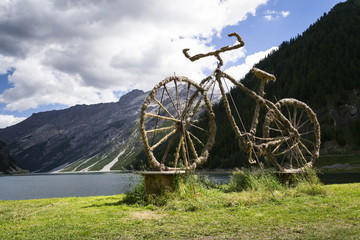 Fototapeta na wymiar Bicycle straw sculpture in front of Lake Livigno, Italy