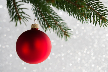 Fototapeta na wymiar Red decorative ball on the xmas tree on glitter bokeh background. Merry christmas card. Winter holiday theme.