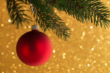 Red decorative ball on the xmas tree on glitter bokeh background. Merry christmas card. Winter holiday theme.