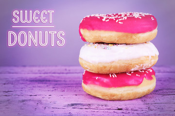 Delicious donuts with icing on table on purple background