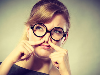 Girl pinches her nose because of stench stink.