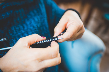 Close up on the hands of a woman knitting with knitting needles and woolen yarn, filtered vintage - handcraft, hobby concept