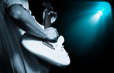 musician playing electric guitar on stage with spotlight