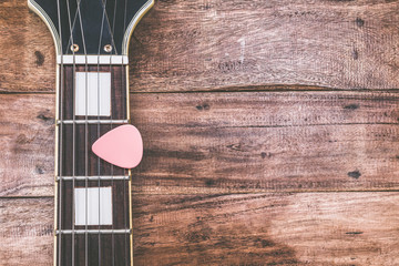 pink pick & electric guitar fretboard, on old wood + vintage filter for music background