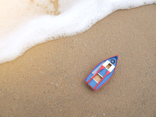 Fototapeta na wymiar Wooden toy boat on the beach