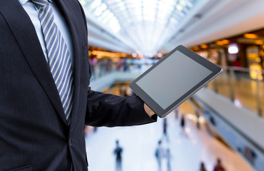 isolated business man hold the tablet on shopping mall background
