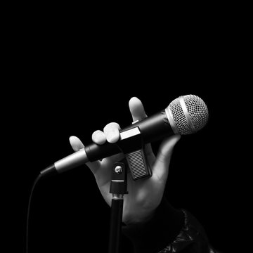 singer right hand holding dynamic microphone, bw filter & isolated on black ( hand sign mean love ) concept = love to sing