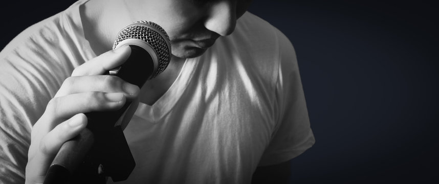 emotion portrait of asian male singer holding microphone, bw filter & isolated on black
