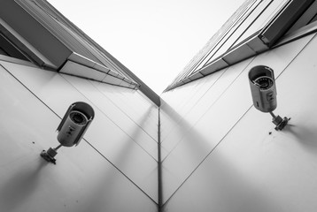 Looking up corner of modern building with security cameras. Office building exterior with...