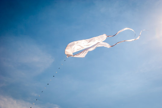 Image of kites flying in the air.  Minimal art and design of isolated white kites flying in the sky. Blue sky background with kites in the sky.