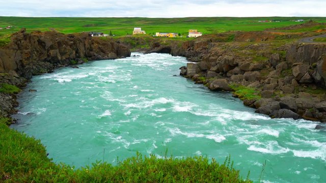 View of flowing water and small village in Iceland