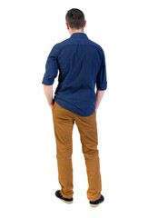 Fototapeta premium Back view of man . Standing young guy. man in a blue shirt with the sleeves rolled up, standing with his hands in his pocket, and looks into the distance.