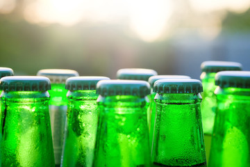 Green glass bottles of beer on the background at sunset with sel