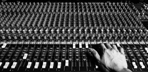 right hand of sound engineer working on recording studio mixer. bw filter