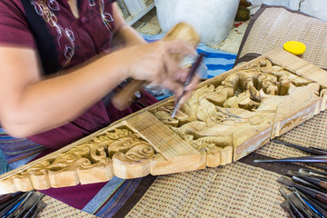 hands of the craftsman carve handmade a bas-relief with a gouge