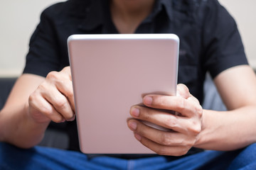 Asian man in black shirt plays his tablet computer