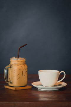 Ice Coffee and Hot Coffee on wood table with dark gray background.