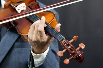 asian male musician playing violin on dark background