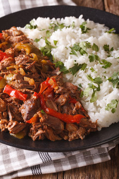 ropa vieja: beef stew in tomato sauce with vegetables and rice garnish close-up. vertical
