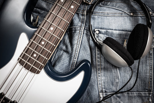 blue electric bass guitar and headphone on denim jeans for music background