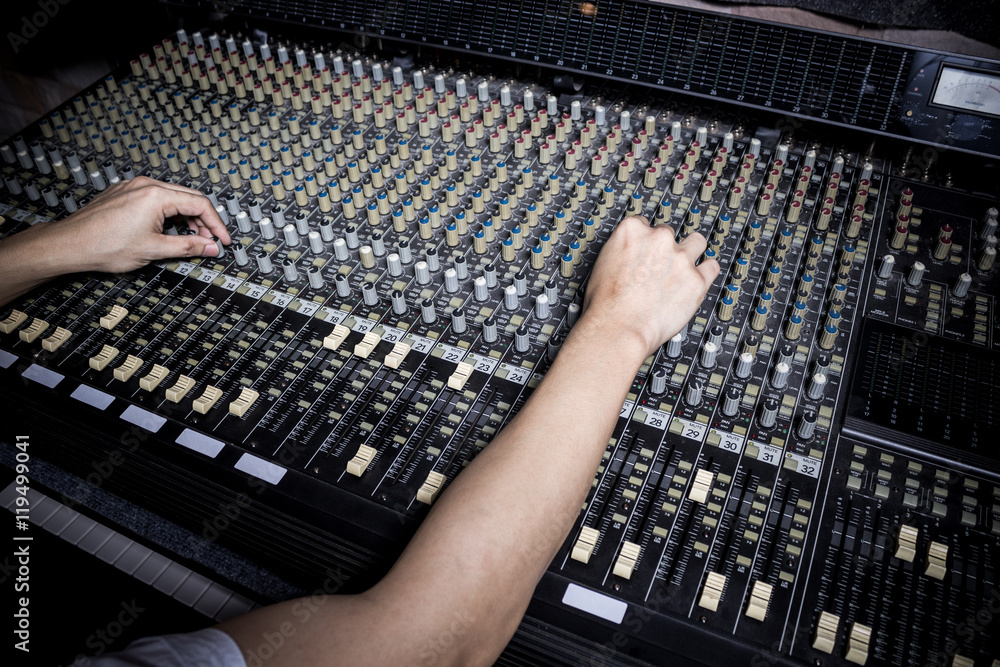 Sticker hands of sound engineer working on recording studio mixer