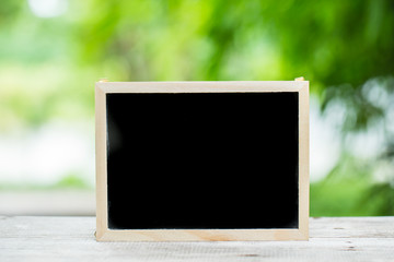 empty black board space for text on wood table with green nature background