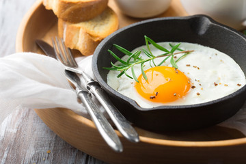 Pan of fried egg, crispy baguette and fruit jam.  Breakfast time