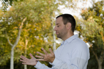Man praying outdoors with his hands extended and open in praise. 