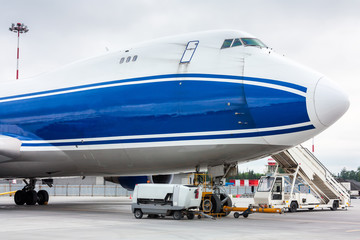 The front of widebody cargo airplane with towbar and passenger step near