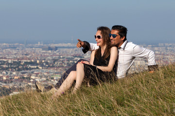 Young multiethnic couple sitting on a hill in European countryside