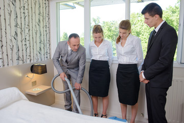 Man showing chamber maids how to vacuum